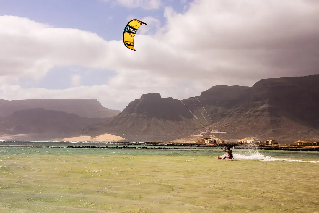 Kitesurfer riding flat water below the mountains of São Vicente